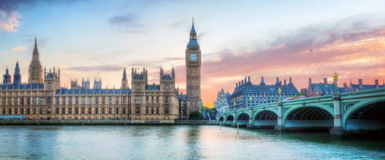 Big Ben and the Palace of Westminster beside Westminster Bridge at sunset in London.