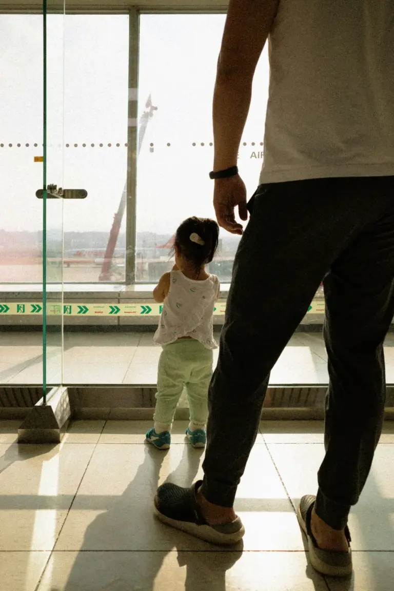 Pai e filha observando um avião pela janela do aeroporto antes de uma viagem